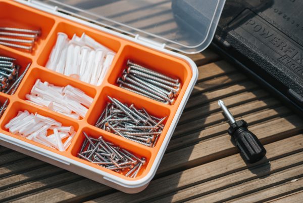 A collection of screws placed inside the tool box on the wooden surface.